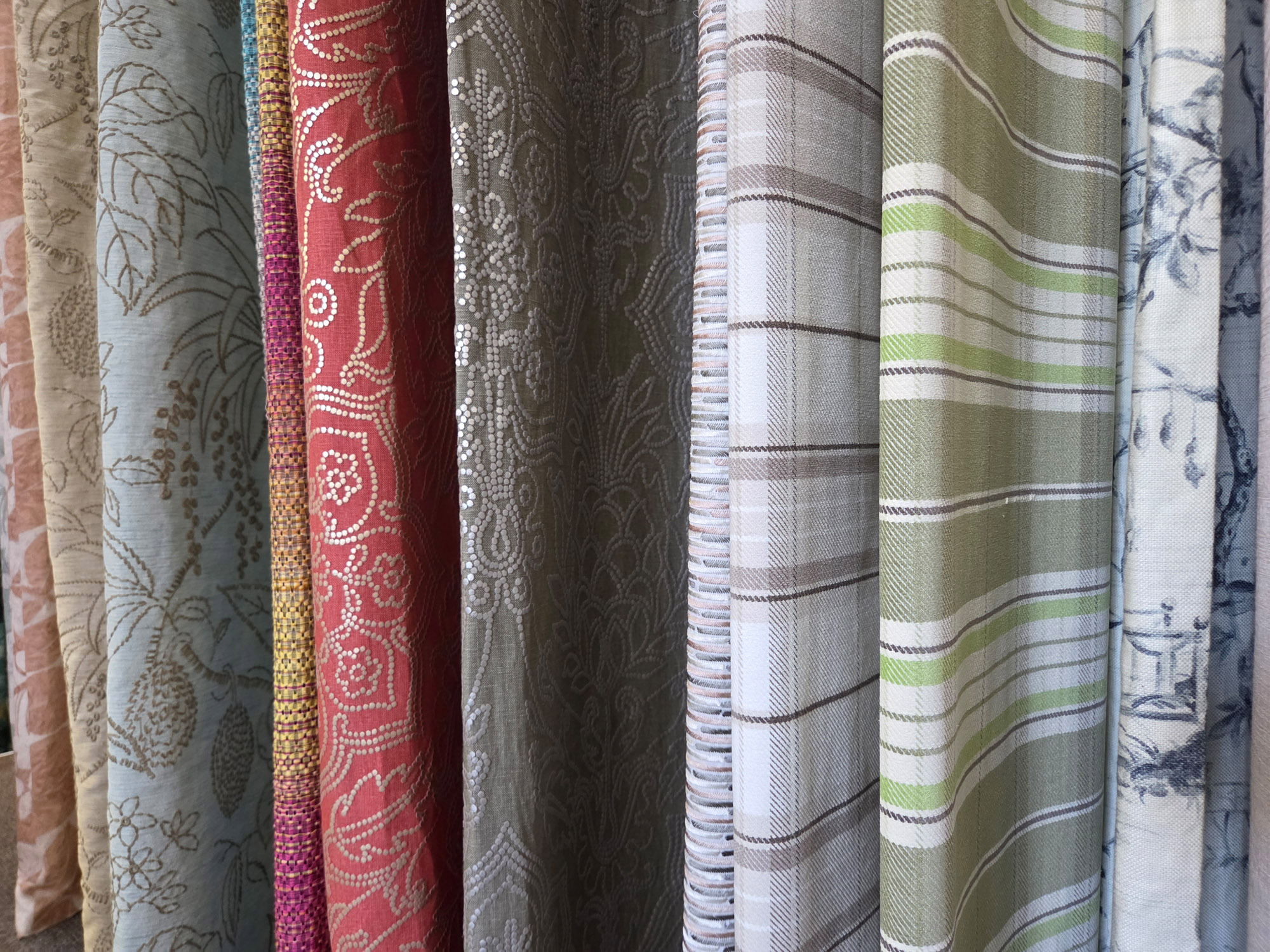 Mehrere unterschiedlich farbige und gemusterte Vorhangstoffe nachhaltig aus Deadstock nebeneinander hängend.
