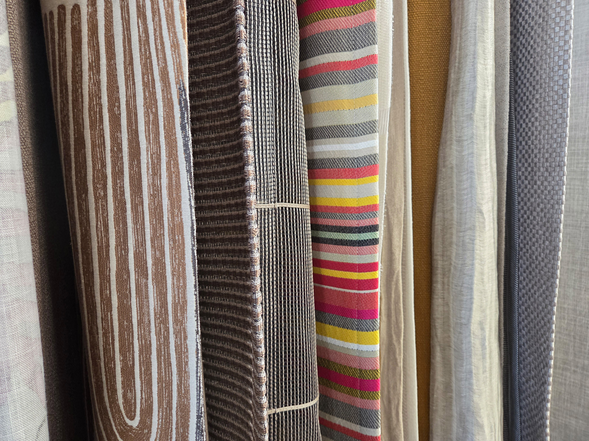 Designer upholstery fabrics in gray and brown tones with different patterns from sustainable deadstock.