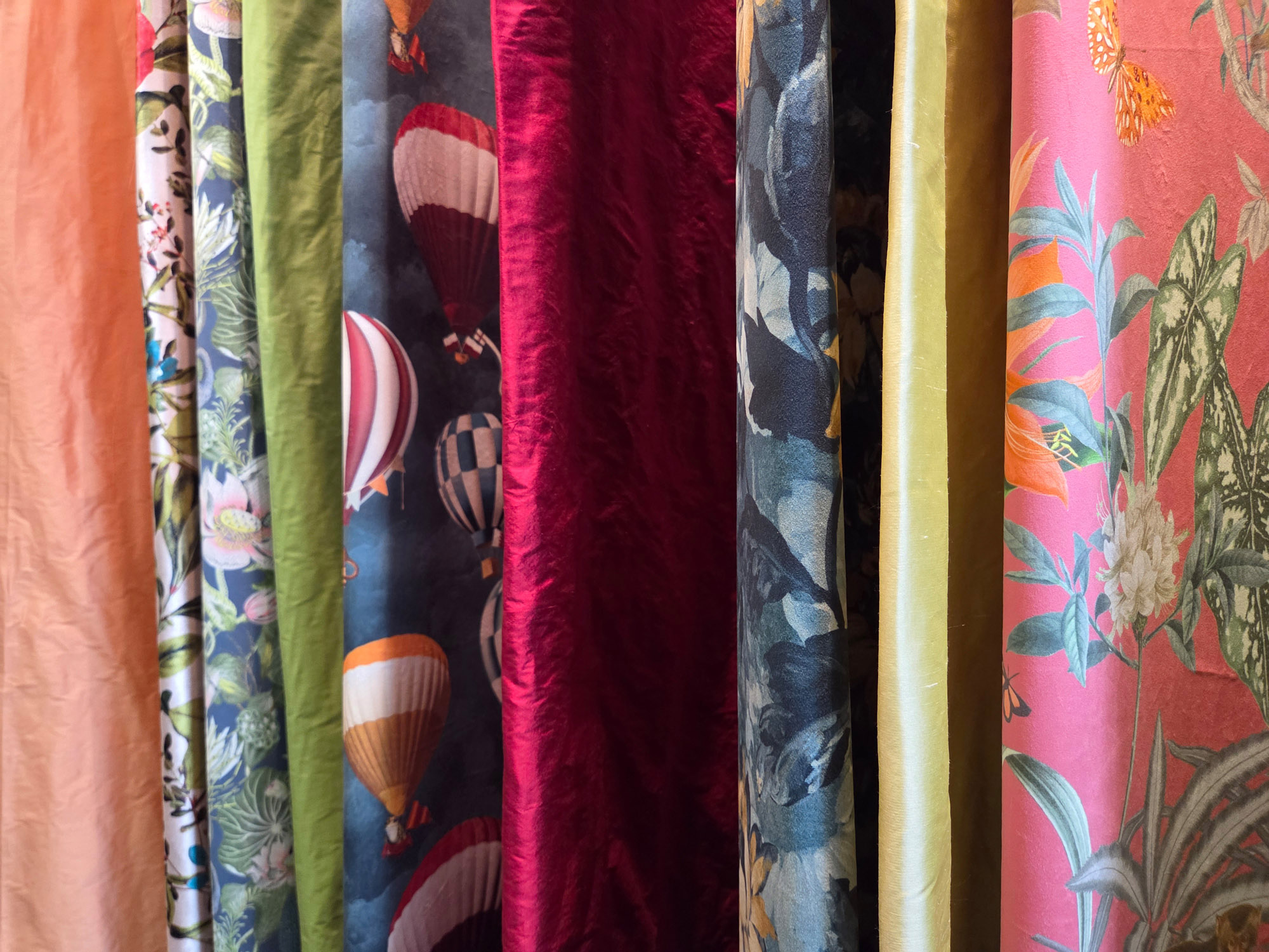 Viele bunt gemusterte Dekostoffe waagerecht hängend, ideal für DIY-Projekte und nachhaltige Meterware.
