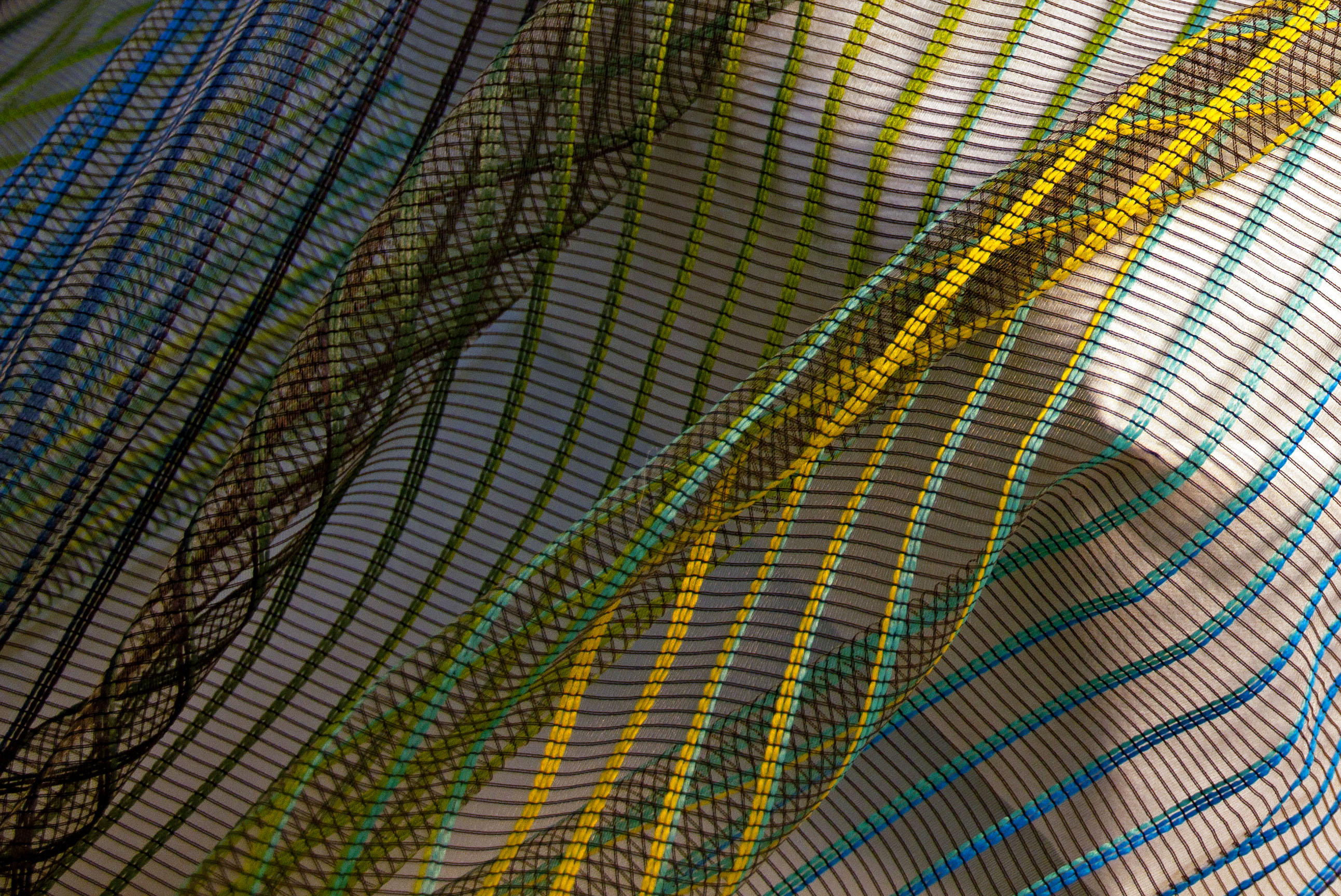 Thin woven fabric with overlapping colorful diagonal lines on a light background, ideal for interior and DIY projects.